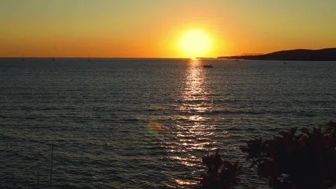 Sunset over calm sea waters with boats visible on the horizon Stock Footage 344813352