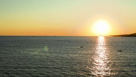 Sunset over calm sea waters with boats visible on the horizon, Stock-Footage 344813503