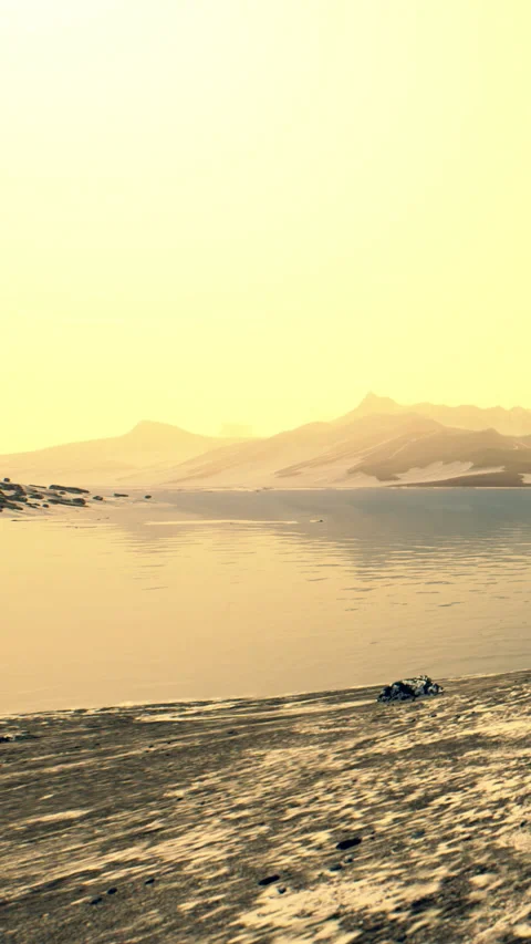 Sunset over calm water and distant mountains with soft sky colors Stock Footage 346758926