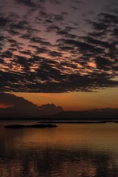 Sunset Over Calm Water With Clouds Stock Photos