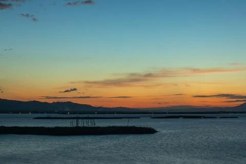 Sunset Over Calm Water with Distant Hills Fotos Stock