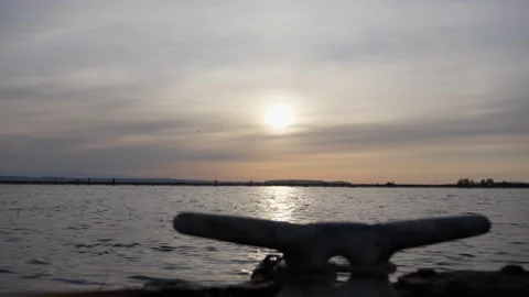 Sunset over calm water with dock cleat in soft focus foreground. 스톡 동영상 312021257