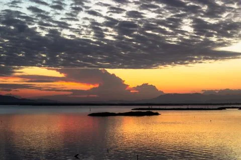 Sunset Over Calm Water with Dramatic Clouds Stock Photos