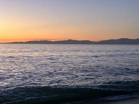 Sunset Over Calm Waters With Distant Mountains in Serene Twilight Glow Stock Photos