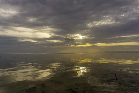 Sunset over calm waters with reflections and dramatic clouds Fotos Stock