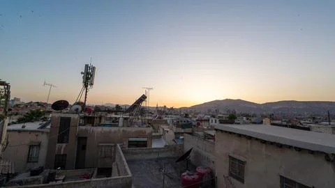 Sunset Over City Rooftops and Distant Mountains Stock Photos