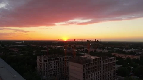 Sunset over city skyline with construction cranes and colorful clouds Stock Footage 339123975