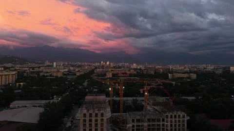 Sunset over city skyline with construction cranes and dramatic clouds Stock Footage 339124153
