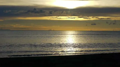 Sunset over a clear horizon, waves gently rolling onto the beach. Stock Footage 32720196
