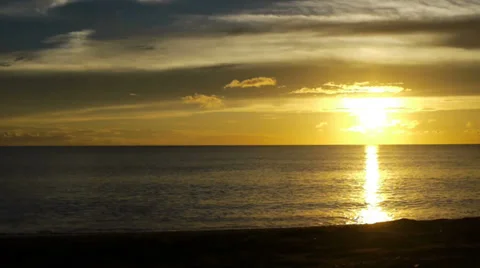 Sunset over a clear horizon, waves gently rolling onto the beach. Stock Footage 32720200