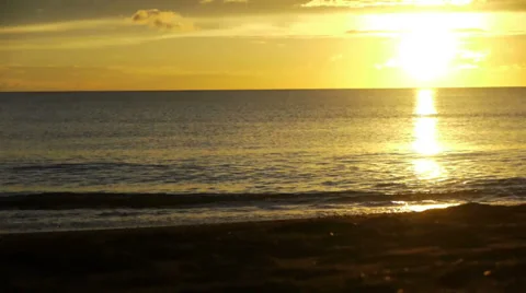 Sunset over a clear horizon, waves gently rolling onto the beach. Stock Footage 32720204