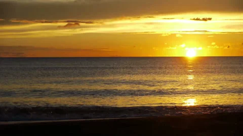 Sunset over a clear horizon, waves gently rolling onto the beach. Stock Footage 32720208