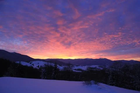 Sunset over the clouds and mountains in winter Stock Photos