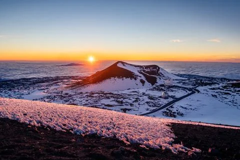 Sunset over clouds from Mauna Kea summit with snow and cinder cones, Hawaii. Stock Photos