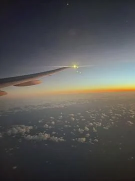 Sunset over the clouds seen from the wing of the plane Stock Photos