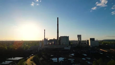 Sunset over an coal mine with smokestacks silhouetted against a clear sky. Stock Footage 307286924