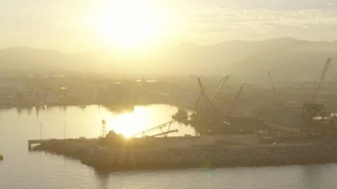 Sunset over a coastal construction site, with cranes silhouetted Stock Footage 324573221