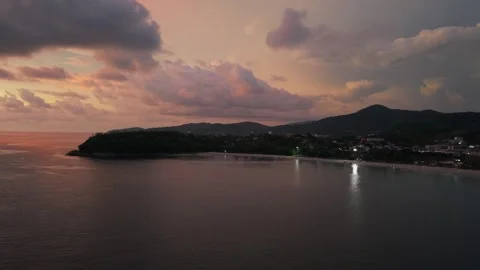 Sunset over coastal landscape with illuminated shoreline and mountains Видео 342312911