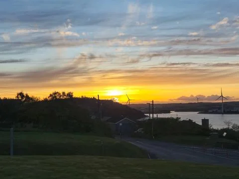 Sunset over coastal landscape with wind turbines 库存照片