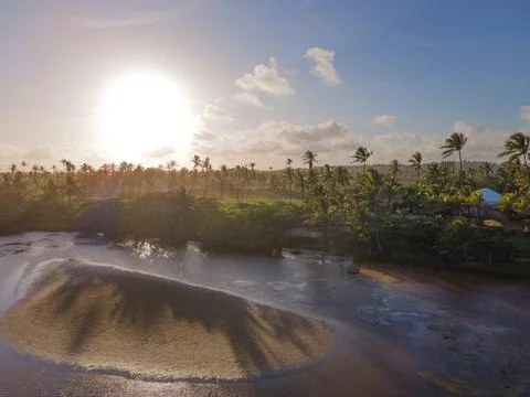 Sunset over coconut trees and river with a few clouds on the sky Foto stock