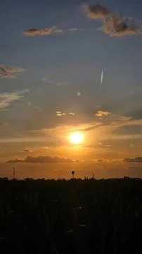 Sunset over a dark landscape with clouds and a bright sun Stock Photos