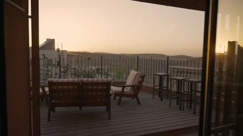 Sunset over desert balcony with lounge chairs and benches overlooking landscape Видео 339074928