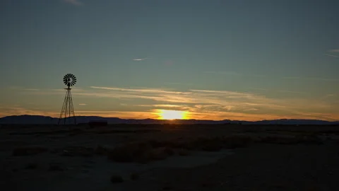 Sunset over desert landscape with windmill Stock Footage 262491694