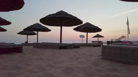 Sunset over a deserted beach and umbrellas after the tourists have left. Stock Footage 285721861