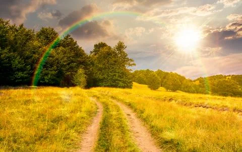 Sunset over dirt road through grassy hills Foto stock