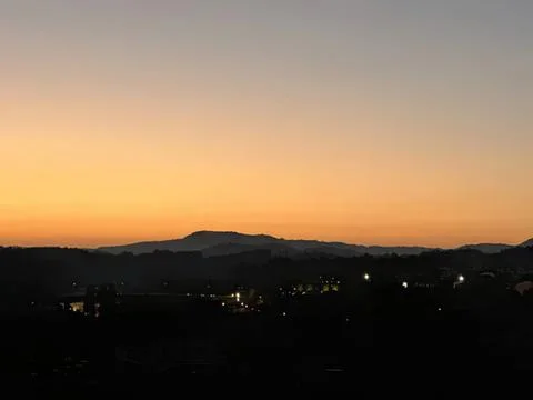 Sunset over distant mountains with city lights below Stock Photos