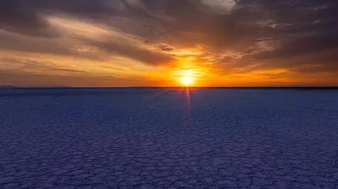 Sunset over a dry salt flat with colorful sky and clouds Stock Photos