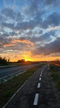 Sunset over empty road with colorful sky and clouds Stock Photos