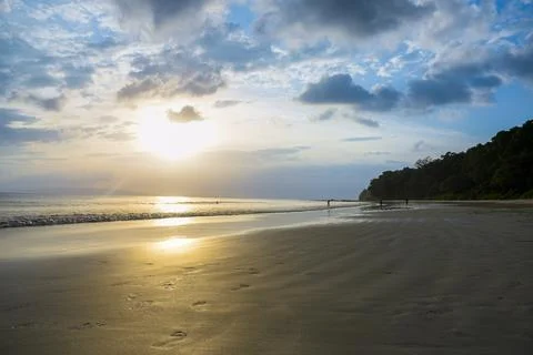 Sunset over empty tropical beach with golden sand, calm sea,cloudy Sky Stock Photos
