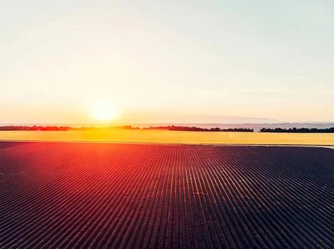 Sunset over farmland with fields and sky Stock Photos