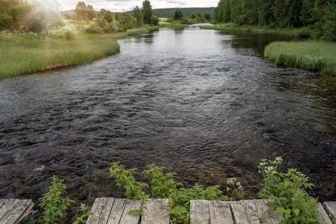 Sunset over fast mountain river with empty wooden batten bridge. Natural te.. Stock Photos