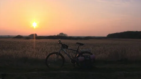 Sunset over the field. Bike and backpack in the foreground. Stock Footage 63441205