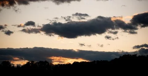 Sunset over forest with dramatic sky and colorful dark clouds Stock Photos