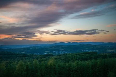 Sunset over forest hills with dramatic evening sky. Stock Photos