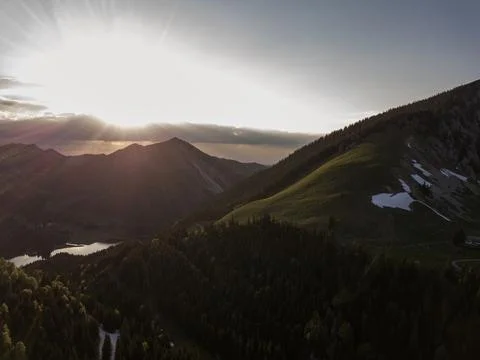 Sunset over forest, lake and snow in the alps Stock Photos