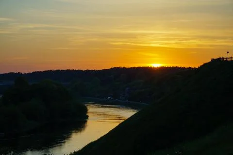Sunset over the forest by the river. Reflection of the sun and sky in the wat Foto stock