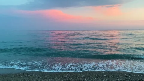 Sunset over gentle waves on a quiet coastal beach Stock Footage 264054774