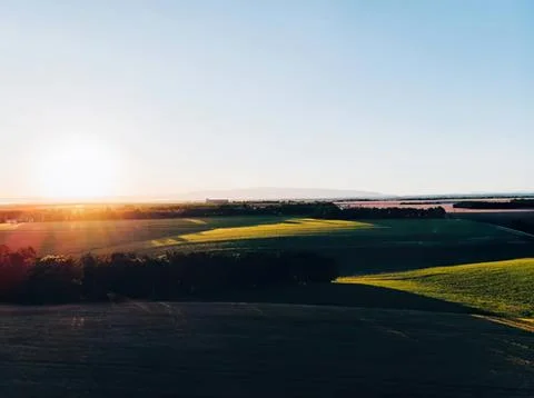 Sunset over green fields and hills in countryside Stock Photos