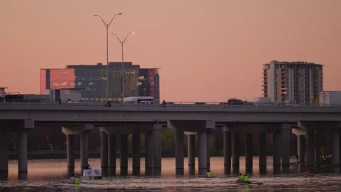 Sunset over highway bridge over water, in front of buildings Stock-Footage 299464054