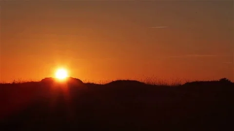Sunset over hill dunes time lapse. Orange sky with fast setting sun over dunes Stock Footage 71316080