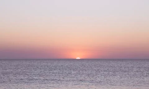 Sunset over the horizon of the ocean with cloudless sky Stock Photos