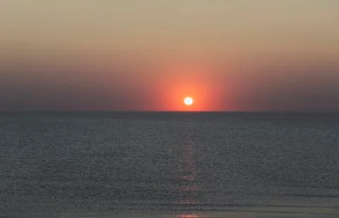 Sunset over the horizon of the ocean with cloudless sky Stock Photos
