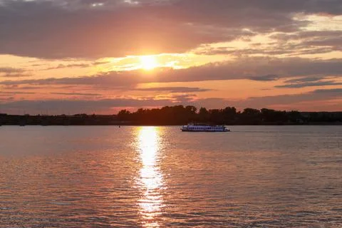 Sunset over the Kama river in Perm Russia and a passing pleasure boat. Stock Photos
