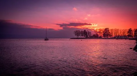 Sunset over lake with backgrounds of trees and clouds. Lausanne, Switzerland. Stock Photos