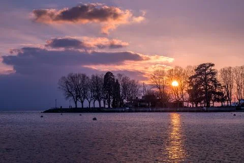 Sunset over lake with backgrounds of trees and clouds. Lausanne, Switzerland. Stock Photos