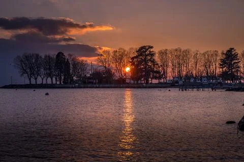 Sunset over lake with backgrounds of trees and clouds. Lausanne, Switzerland. Stock Photos